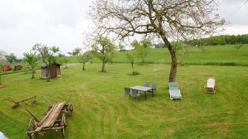 a table and chairs and a tree in a field at Le Cerisier - Bel Appt pour 4 personnes in Puberg
