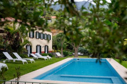 a pool in the yard of a house with chairs at Casa Da Piedade in São Vicente