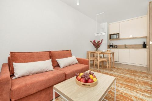 a living room with a couch and a bowl of fruit on a table at Sun & Beach Apartments Bel Mare with Parking by Noclegi Renters in Międzyzdroje