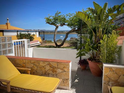 a yellow bench sitting on a stone wall with plants at Villa Cristipaulo in Praia de Faro