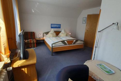 een slaapkamer met een bed, een tv en een bureau bij Haus Minor in Borkum