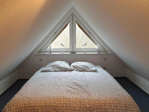 een slaapkamer met een bed en een groot raam bij Huus 24 in Borkum