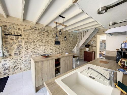 une cuisine avec un évier et un mur en pierre dans l'établissement Ker Avel Maison Bretonne, à Quiberon