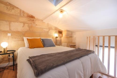 sypialnia z łóżkiem z kamienną ścianą w obiekcie Appartements - Bordeaux Centre Gare w mieście Bordeaux