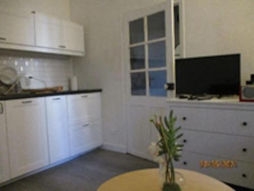 - une cuisine avec des placards blancs et une table avec un vase dans l'établissement Bandol - City Center - Small One Bedroom Flat, à Bandol