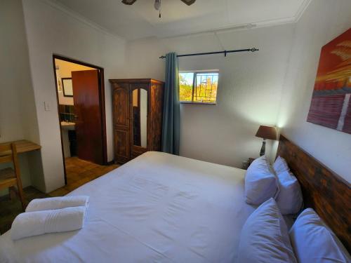 a bedroom with a large bed with white sheets and pillows at Pine Valley in Lanseria