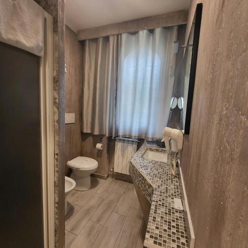 a bathroom with a sink and a toilet and a window at ILLUVIA 2 AFFITTA CAMERE in Cornaredo