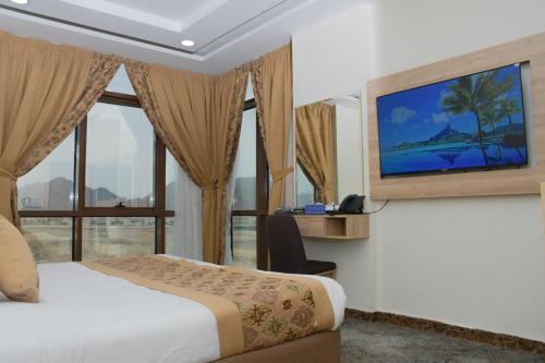 una camera d'albergo con letto e televisore a parete di فندق ريست ان a Qabāʼ