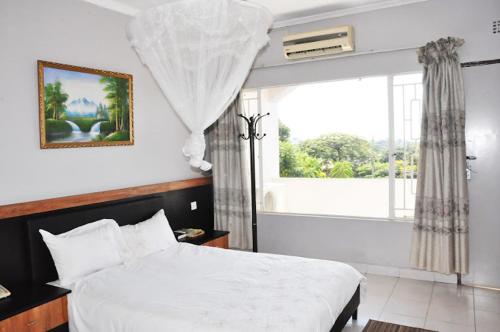 a bedroom with a white bed and a window at CROWN HOTEL INTERNATIONAL in Lilongwe