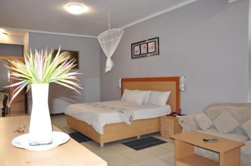 CROWN HOTEL INTERNATIONAL في ليلونغوي: غرفة نوم بسرير و مزهرية بها نبات