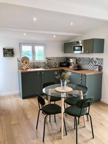 une cuisine avec des armoires vertes, une table et des chaises dans l'établissement Le Cabanon de la Sainte Baume, à Roquevaire
