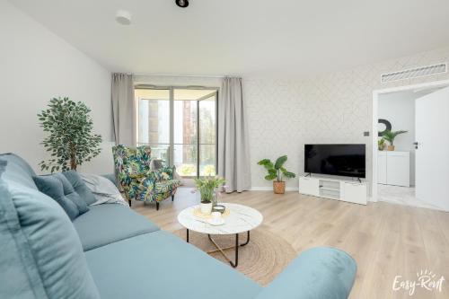 a living room with a blue couch and a table at Prestige Dream 104 - tuż przy plaży, z widokiem na morze, parkingiem i WiFi w cenie pobytu - Easy-Rent Apartments in Pobierowo