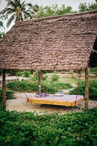 a swing with a thatched roof on top of it at Maisara Mafia Beach Lodge in Kilindoni