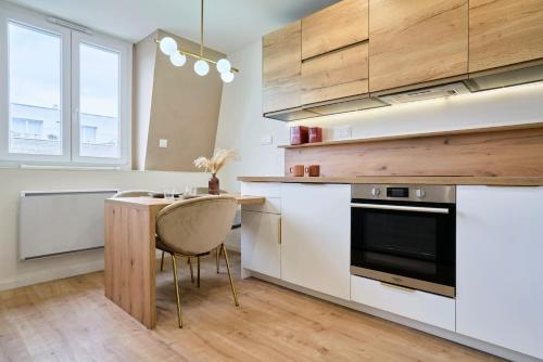 une cuisine avec des armoires blanches et une table en bois dans l'établissement T2-spacieux-lumineux, à Mons-en-Baroeul