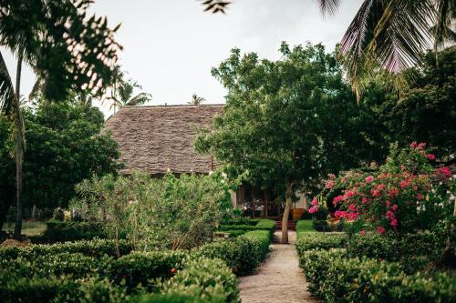 a garden with trees and flowers and a building at Maisara Mafia Beach Lodge in Kilindoni
