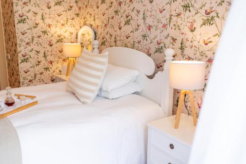 a bedroom with a white bed and floral wallpaper at Casa Da Piedade in São Vicente