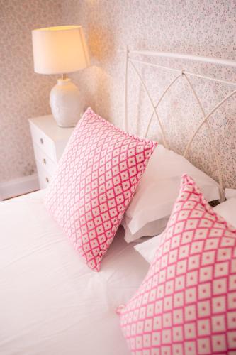 a bed with pink and white pillows on it at Casa Da Piedade in São Vicente
