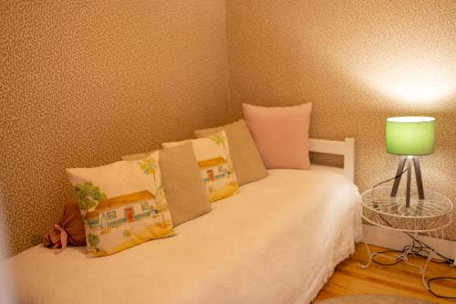 a bedroom with a bed with pillows and a green lamp at Casa Da Piedade in São Vicente