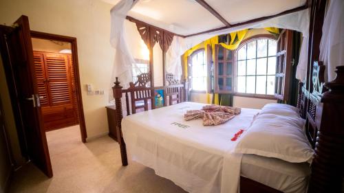 - une chambre avec un lit à baldaquin et des draps blancs dans l'établissement Tembo Beach Apartments, à Malindi