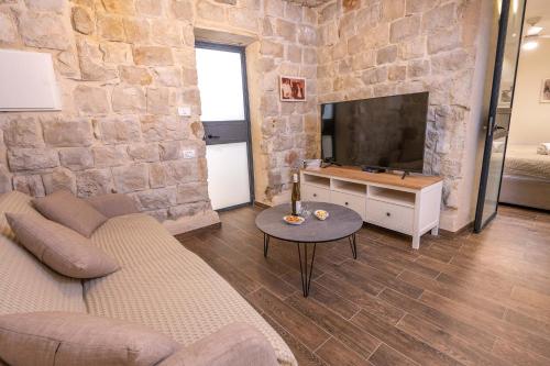 a living room with a couch and a tv at ארגמן סוויטות בוטיק in Safed