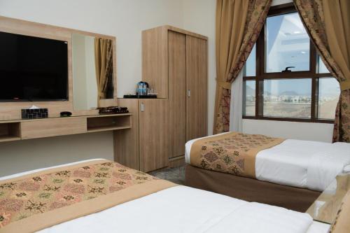 um quarto de hotel com duas camas e uma televisão em فندق ريست ان em Qabāʼ