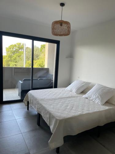 une chambre avec un lit et une grande fenêtre dans l'établissement Bel appartement spacieux à Porto-Vecchio, 10min à pieds du centre ville, à Porto-Vecchio
