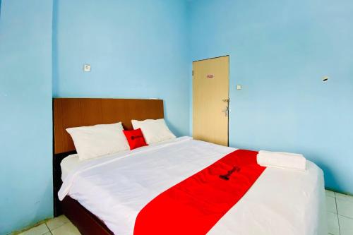 a bedroom with a large bed with red and white sheets at RedDoorz at Star Hill Inn Syariah Tebing Tinggi in Tebingtinggi