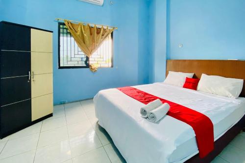 a bedroom with a large bed and a window at RedDoorz at Star Hill Inn Syariah Tebing Tinggi in Tebingtinggi