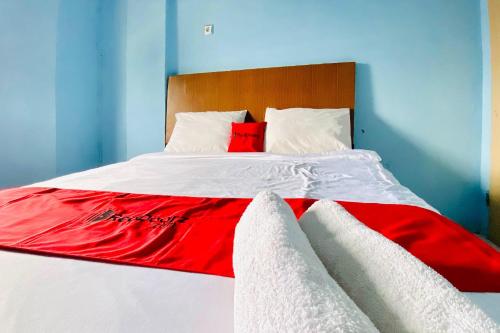 a bed with red and white sheets and pillows at RedDoorz at Star Hill Inn Syariah Tebing Tinggi in Tebingtinggi