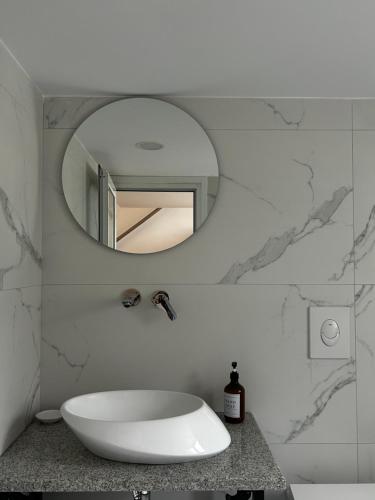 uma casa de banho com um espelho redondo e um lavatório em Vourtaréa Guesthouse em Himare