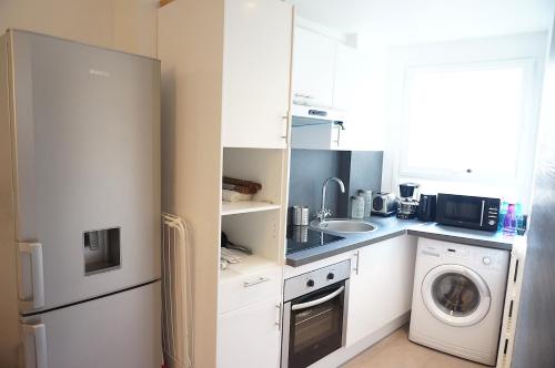 une cuisine avec des armoires blanches et une laveuse et une sécheuse dans l'établissement Montparnasse 1BDR, à Paris