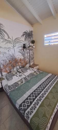 a bedroom with a bed with palm trees on the wall at Joli studio Coeur de Canne piscine et plage en Martinique in Les Trois-Îlets