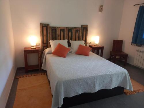 a bedroom with a large bed with two orange pillows at Veiga Mariña in A Xesteira