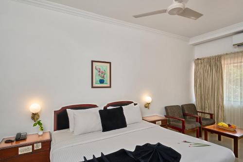 a bedroom with a large white bed and chairs at Abad Fort in Cochin