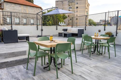 a patio with tables and chairs on a rooftop at ארגמן סוויטות בוטיק in Safed