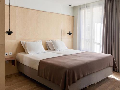 una camera da letto con un grande letto con cuscini bianchi di New Hotel Opéra a Parigi