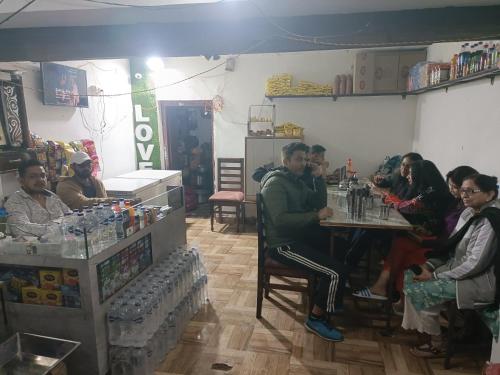 a group of people sitting at a table in a store at Hotel New Sunrise in Phata