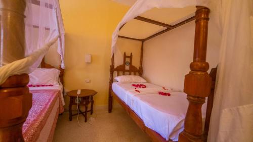 a bedroom with two beds with red roses on them at Tembo Oceanic Apartments in Malindi