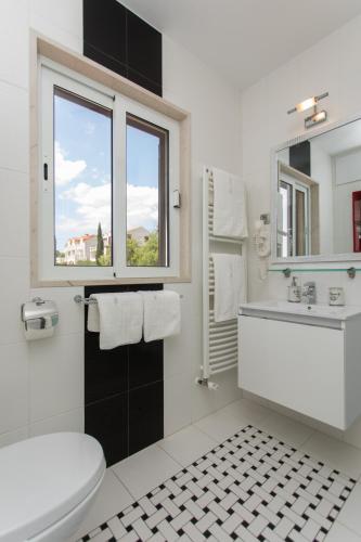 a bathroom with a toilet and a sink and a window at Apartments Villa Nena in Bol