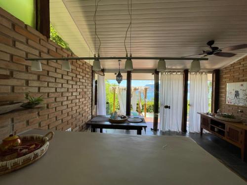 a living room with a table and a brick wall at Villa Villagio di Mare in Ilhabela