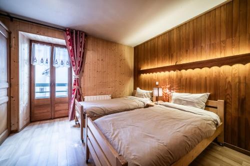 two beds in a room with wooden walls and a window at L' Abbaye in Abondance