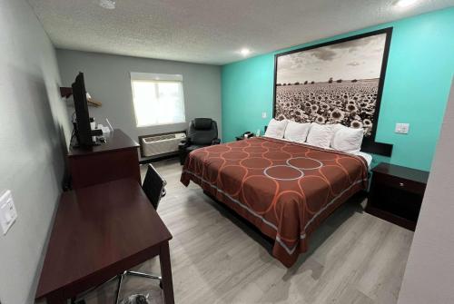 a hotel room with a bed and a picture of a football game at Super 8 by Wyndham Emporia in Emporia