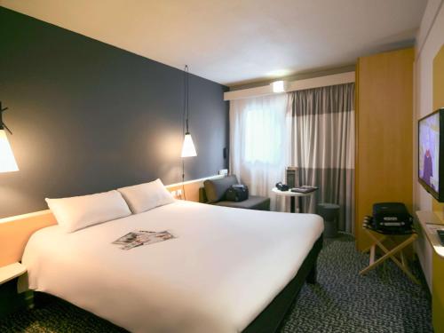 ナントにあるIbis Nantes la Beaujoire Parc Expoの大型ベッドとテレビが備わるホテルルームです。