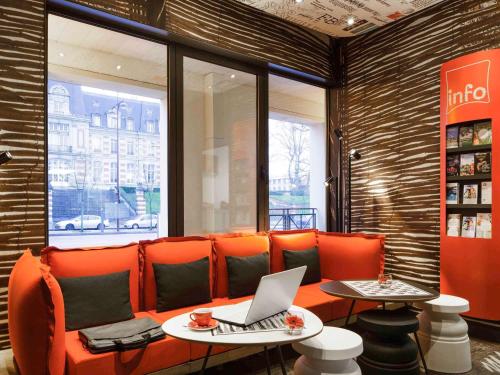 a restaurant with an orange couch with a laptop on it at ibis Versailles Château in Versailles