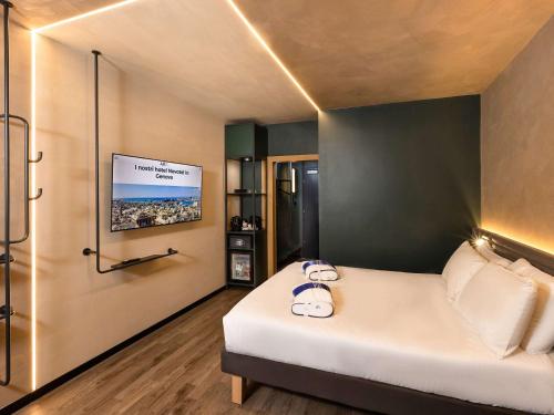 Habitación con cama y TV en la pared. en Novotel Genova City, en Génova