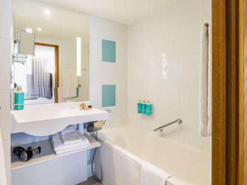 فندق نوفوتيل بروكسل أوف غراند بلاس في بروكسل: حمام أبيض مع حوض وحوض استحمام وحوض استحمام