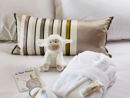 łóżko z ręcznikiem, wypchane zwierzę i książka w obiekcie Sofitel Biarritz Le Miramar Thalassa w Biarritz