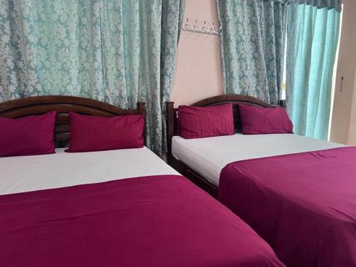 2 letti posti uno accanto all'altro in una camera da letto di OYO 90981 Chenang Rest House 1 a Pantai Cenang