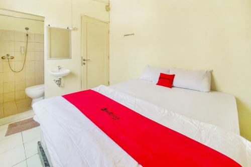 Un dormitorio con una cama roja y blanca y un baño. en RedDoorz near bandara City Mall, en Tangerang