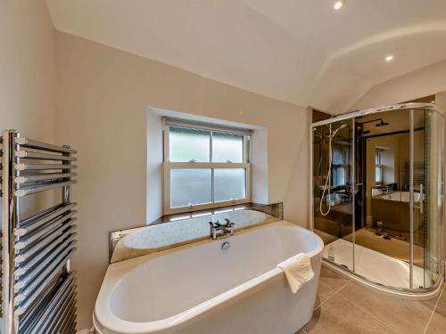 baño con bañera blanca y ventana en 3 Bed in Aberdovey DY029 en Aberdyfi